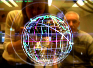Bright projection of a globe apparently onto a transparent screen or floating, behind which a man and woman are seen