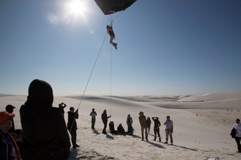 black balloon, person suspended, white desert, blue sky